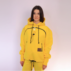 Person wearing a yellow hoodie with black drawstrings on a light purple background